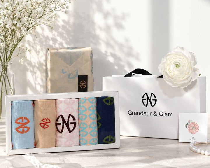 GAILESH gift set with five patterned fashion socks in a clear-lid presentation box, shown with the Grandeur & Glam gift bag, wrapped gift box, message card, and floral styling.